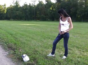 Skinny babe lies down on the grass and passionately masturbates pussy